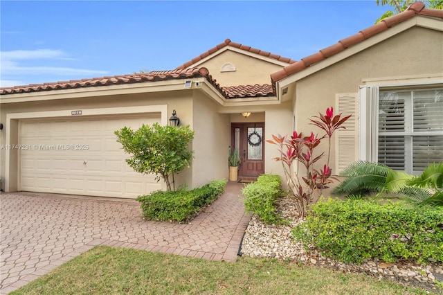 view of front of home with a garage, a tile roof, decorative driveway, and stucco siding