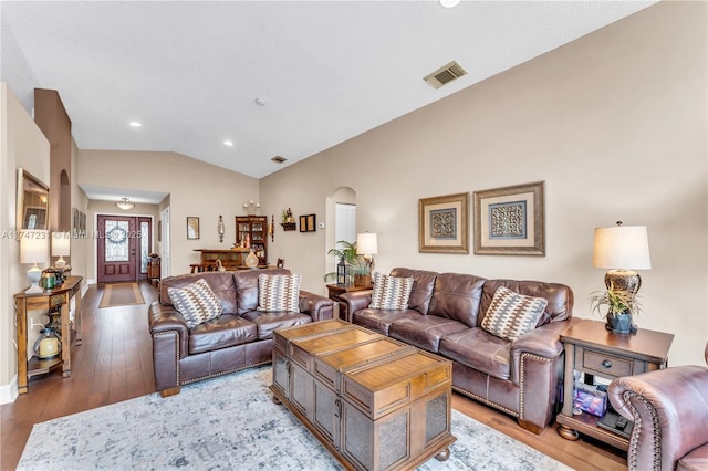 living area featuring arched walkways, lofted ceiling, recessed lighting, visible vents, and light wood-style flooring