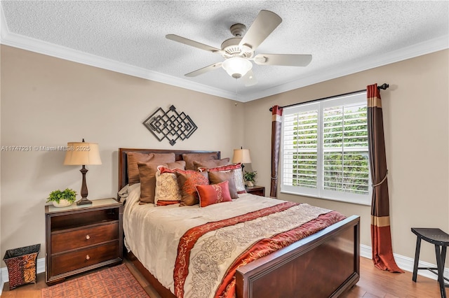 bedroom featuring ornamental molding, baseboards, a textured ceiling, and light wood finished floors