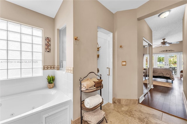 ensuite bathroom featuring ensuite bathroom, a ceiling fan, a stall shower, a textured ceiling, and a whirlpool tub