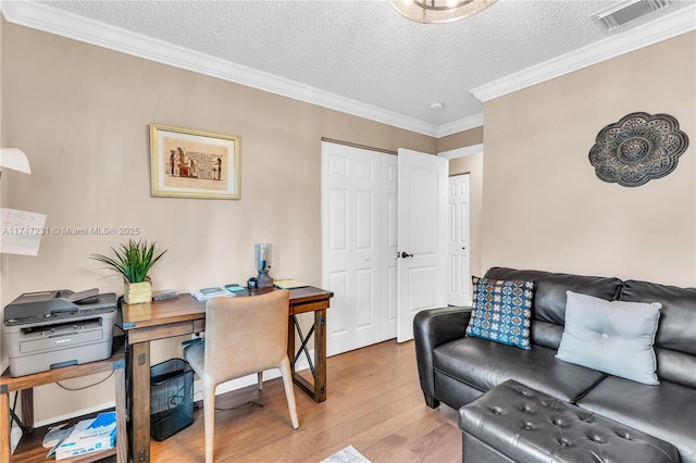 office space featuring a textured ceiling, ornamental molding, wood finished floors, and visible vents