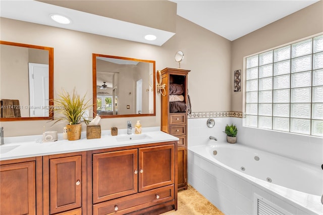 bathroom with double vanity, tile patterned flooring, a tub with jets, and a sink