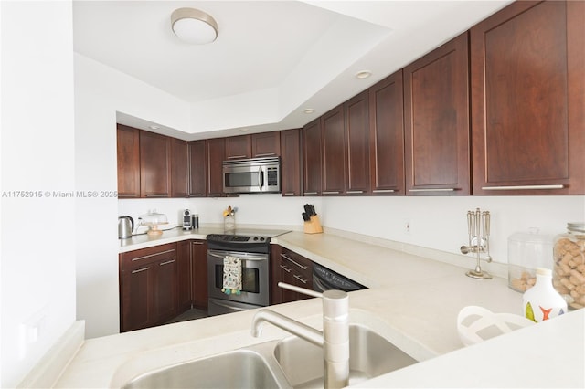 kitchen featuring a sink, a peninsula, stainless steel appliances, and light countertops