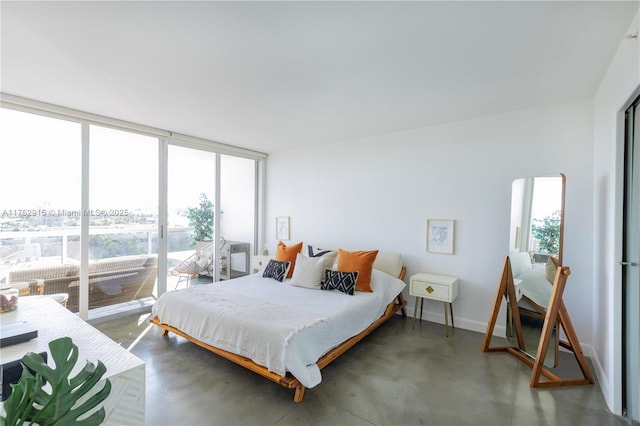 bedroom with access to exterior, a wall of windows, baseboards, and finished concrete floors