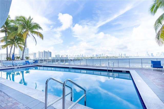 view of swimming pool with a view of city and a water view