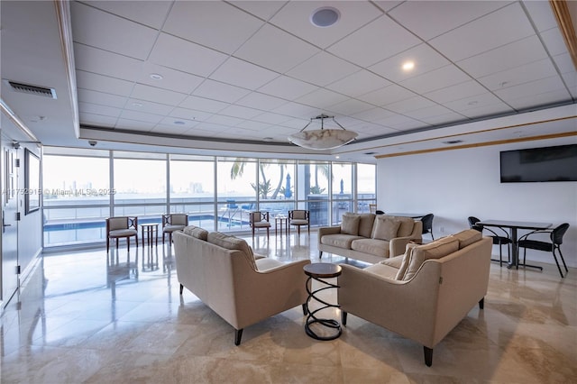 living area with a tray ceiling, a wall of windows, a water view, and visible vents