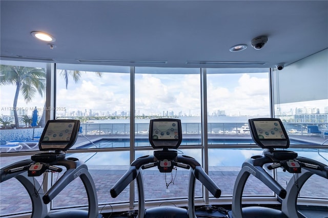 workout area with expansive windows, a water view, and a view of city