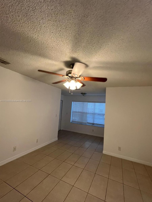 unfurnished room featuring light tile patterned floors, a textured ceiling, visible vents, baseboards, and a ceiling fan