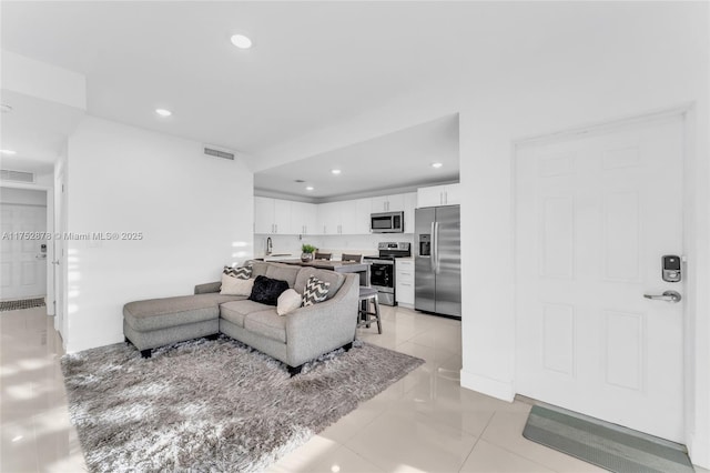 living room featuring light tile patterned flooring, baseboards, visible vents, and recessed lighting