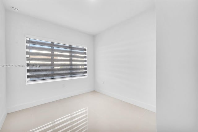 empty room featuring light tile patterned floors and baseboards