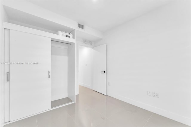 unfurnished bedroom featuring light tile patterned floors, a closet, visible vents, and baseboards