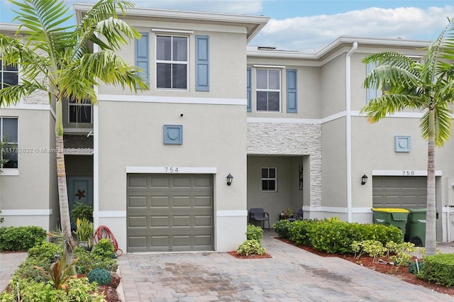 view of property featuring a garage, decorative driveway, and stucco siding