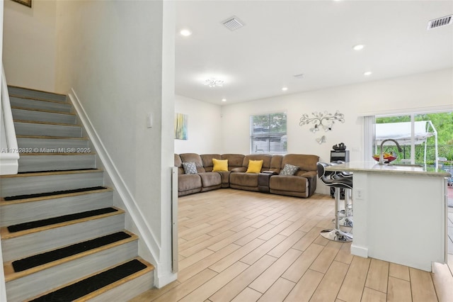 living area with wood tiled floor, visible vents, stairway, and recessed lighting