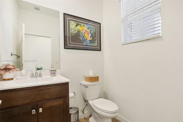 bathroom featuring toilet, vanity, visible vents, and baseboards