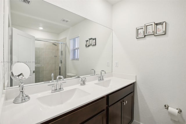 bathroom with double vanity, visible vents, toilet, a sink, and a shower stall