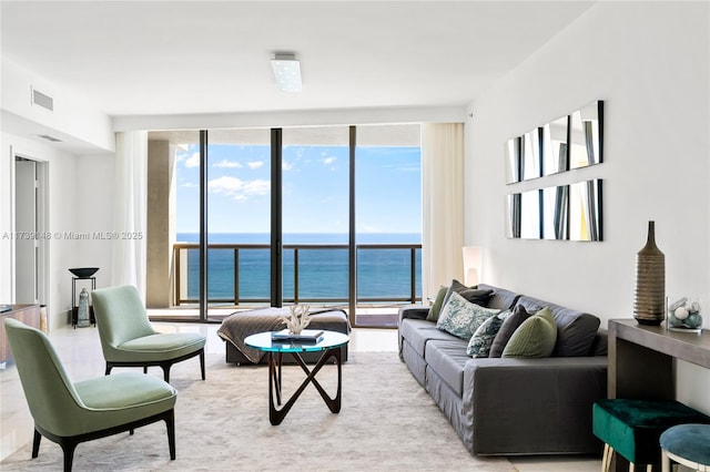 living room with expansive windows, a water view, and visible vents