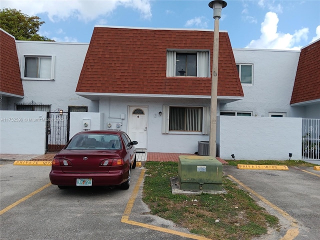 townhome / multi-family property featuring stucco siding, mansard roof, and roof with shingles