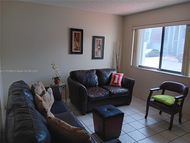 living area featuring light tile patterned floors, baseboards, and a textured ceiling