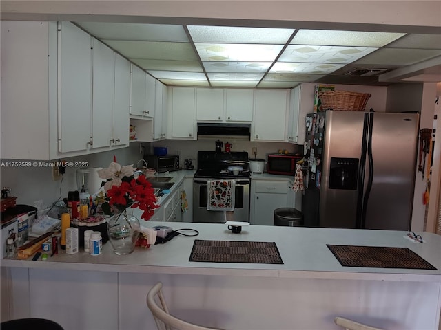 kitchen featuring stainless steel appliances, a paneled ceiling, light countertops, and under cabinet range hood