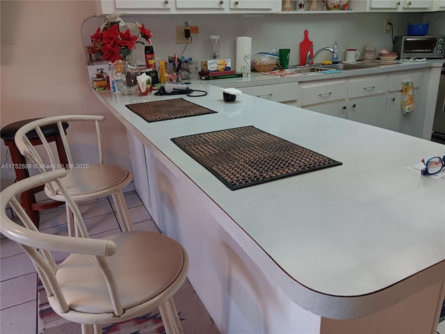 kitchen featuring light tile patterned floors, a toaster, light countertops, white cabinetry, and a sink