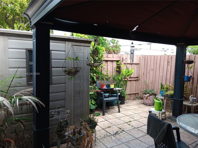 view of patio with a storage unit, fence, and an outbuilding