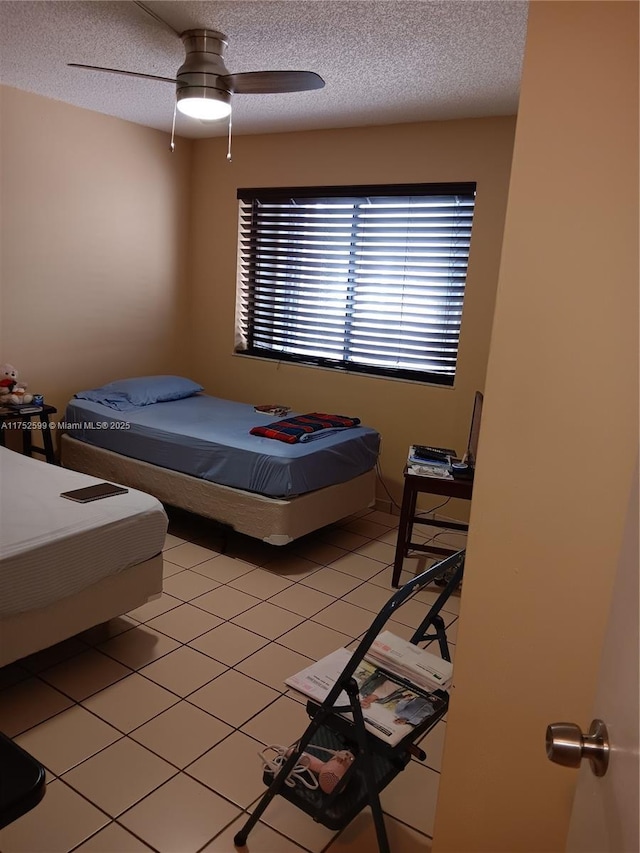 bedroom with a textured ceiling, ceiling fan, and light tile patterned floors