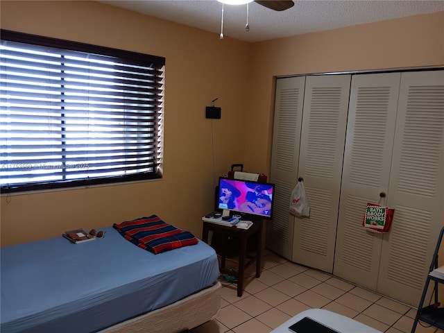 bedroom featuring light tile patterned floors, multiple windows, a closet, and a textured ceiling