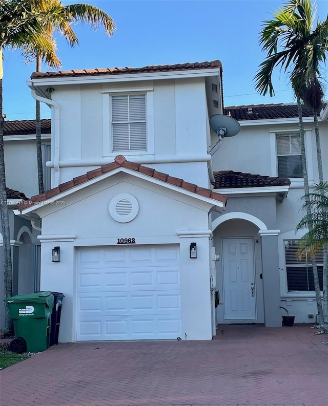 view of front of house featuring stucco siding, a tiled roof, decorative driveway, and a garage