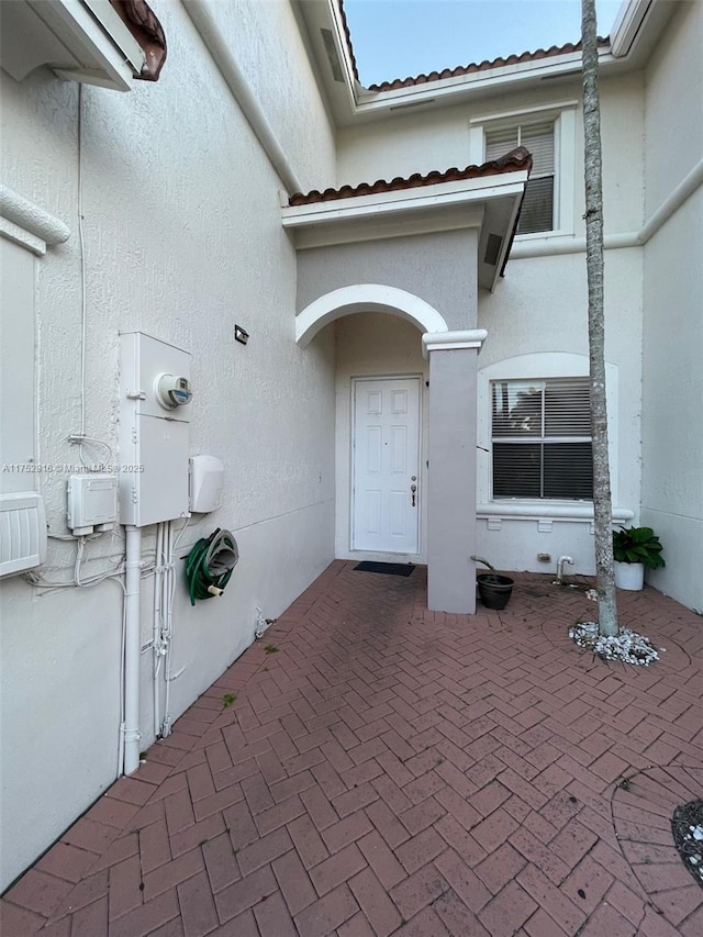 doorway to property featuring a patio area, a tile roof, and stucco siding