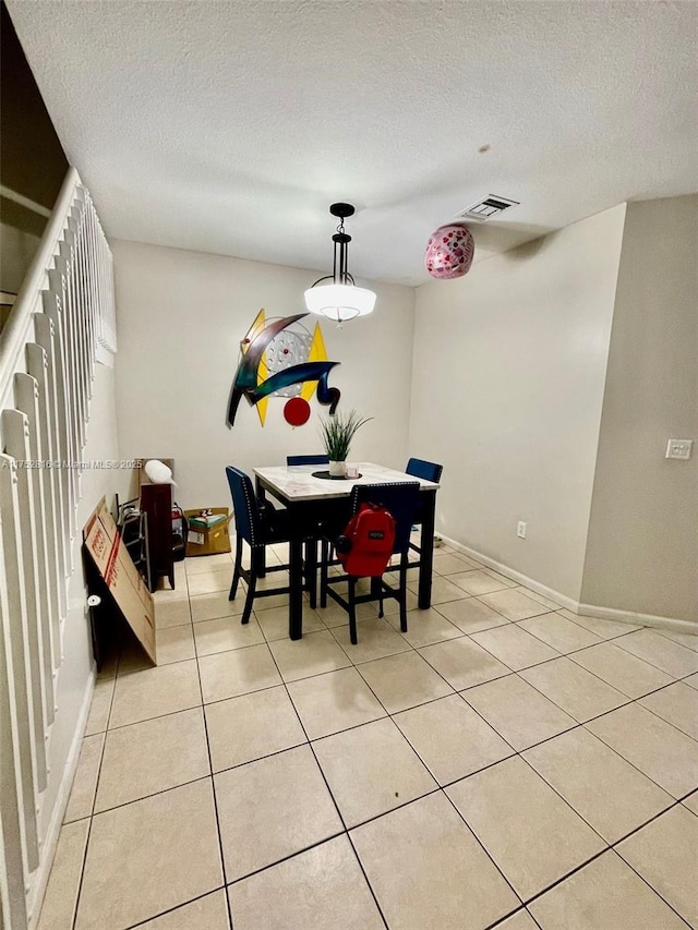 dining space with a textured ceiling, light tile patterned flooring, visible vents, and baseboards