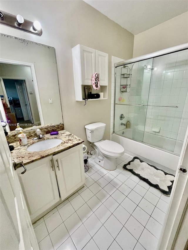 full bath featuring tile patterned flooring, combined bath / shower with glass door, vanity, and toilet