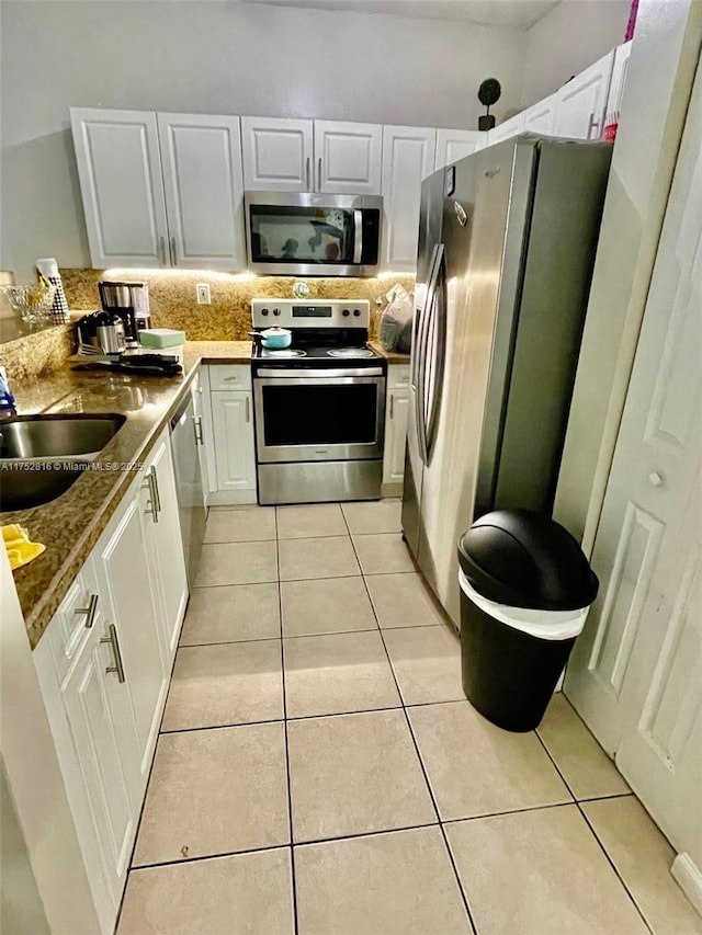 kitchen featuring stainless steel appliances, a sink, decorative backsplash, and light tile patterned floors