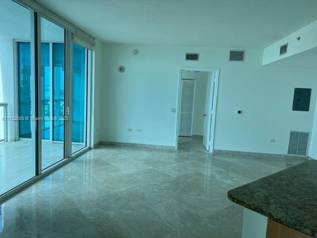 empty room featuring expansive windows, a healthy amount of sunlight, and visible vents