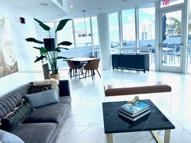 living area featuring marble finish floor and a wall of windows