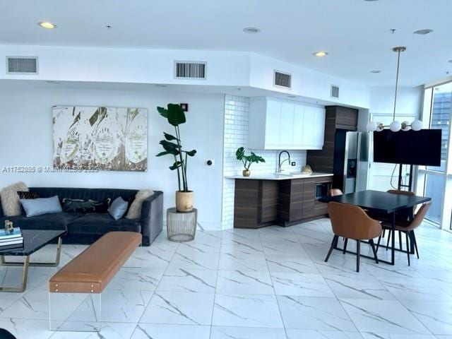 interior space featuring marble finish floor, visible vents, light countertops, and stainless steel fridge with ice dispenser