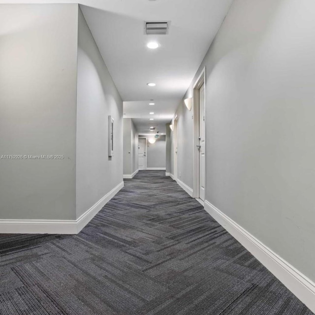 corridor featuring recessed lighting, visible vents, dark carpet, and baseboards