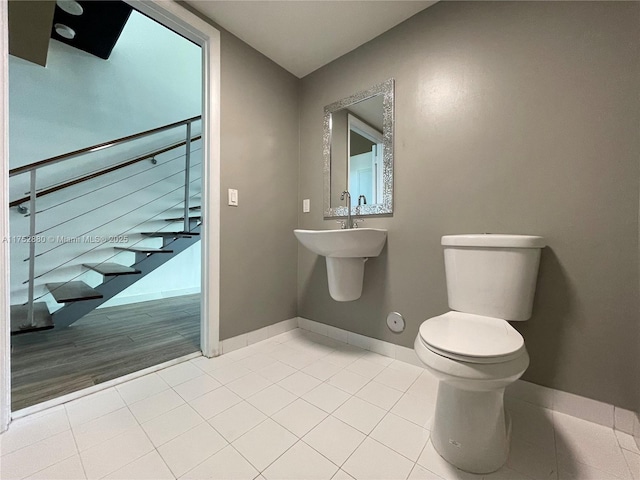 half bath featuring tile patterned flooring, baseboards, and toilet