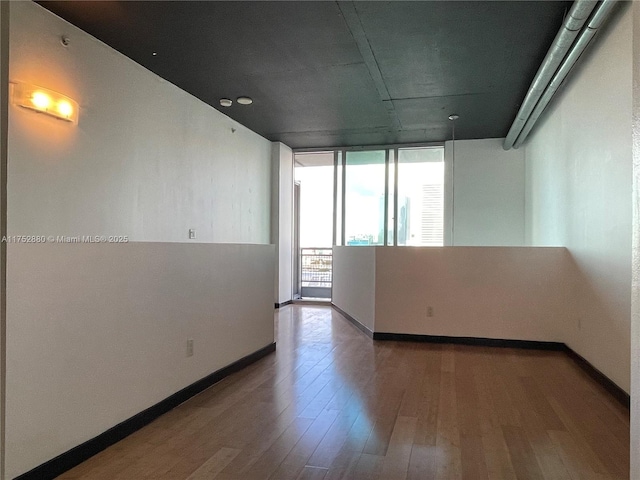 spare room featuring baseboards and wood finished floors