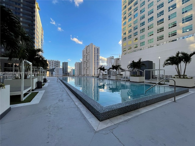 community pool with a patio area and a city view