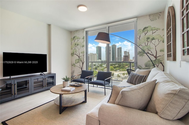 living area with a wall of windows, a view of city, and wood finished floors