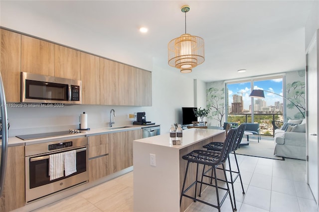 kitchen featuring a center island, stainless steel appliances, light countertops, a wall of windows, and a kitchen bar