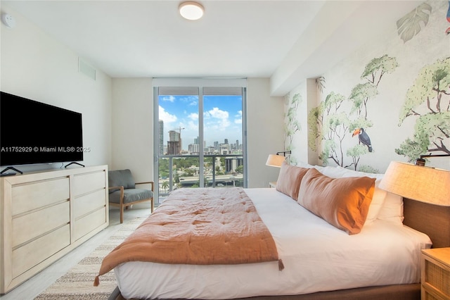 bedroom with a view of city, access to outside, a wall of windows, and visible vents