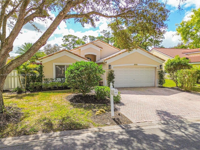 mediterranean / spanish-style house with an attached garage, a tiled roof, decorative driveway, stucco siding, and a front yard