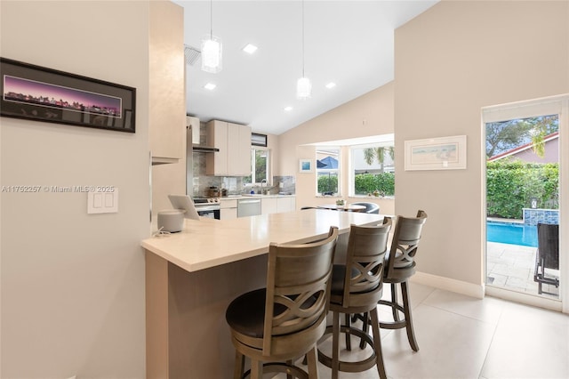 kitchen featuring decorative light fixtures, a breakfast bar area, stainless steel appliances, light countertops, and a peninsula