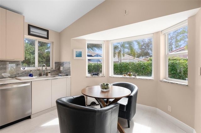 kitchen with decorative backsplash, dishwasher, vaulted ceiling, light countertops, and a sink