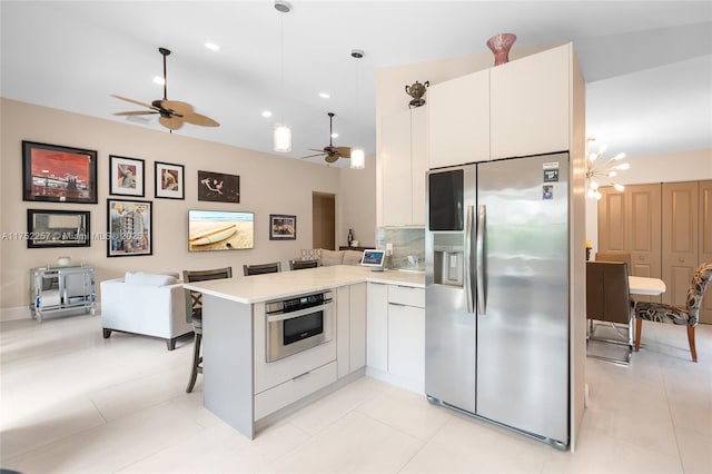 kitchen with appliances with stainless steel finishes, open floor plan, a kitchen breakfast bar, a peninsula, and white cabinetry