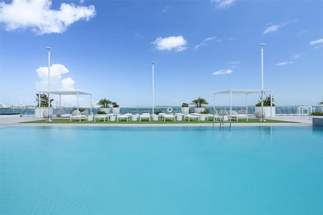 view of swimming pool featuring a water view and fence