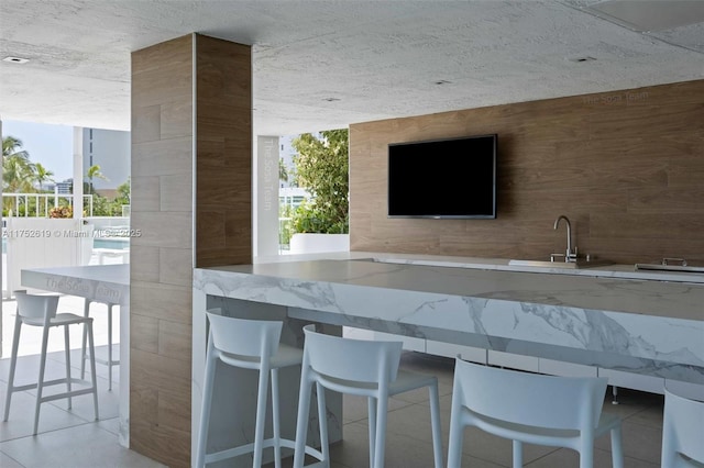 bar featuring a wall of windows, a sink, and tile patterned floors