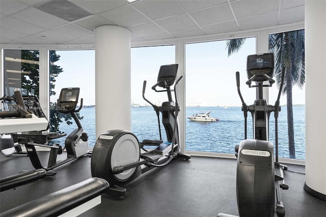 exercise room with a water view, expansive windows, and a paneled ceiling