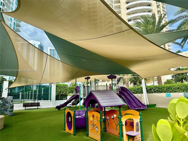 community play area featuring fence and a lawn